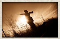 Hunter overlooking field at sunset with dog